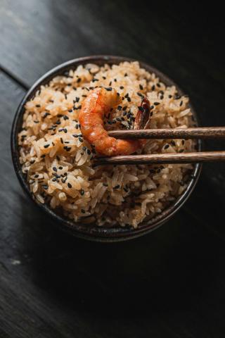 Chopsticks holding shrimp over bowl of rice - indicative photo for the Prawn Dishes group
