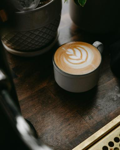 a cappuccino sitting on top of a wooden table - indicative photo for the Beverages group