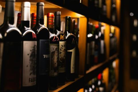 Wine bottles line shelves in a dimly lit room - indicative photo for the Red Wine 750ml group