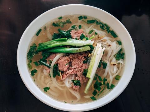 Bowl of pho with sliced beef, rice noodles and spring onion