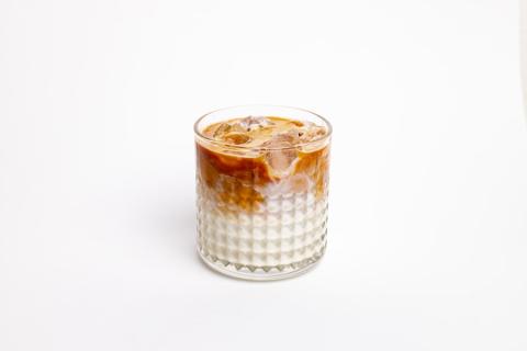 Iced coffee layered over condensed milk in a glass